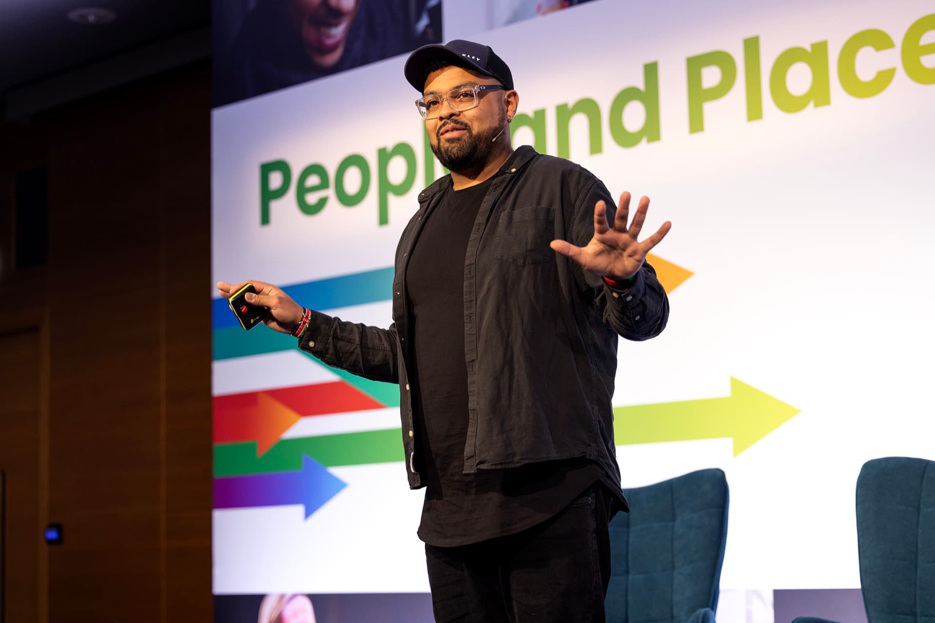 Tom Kegode keynoting in front of a People and Places stage screen